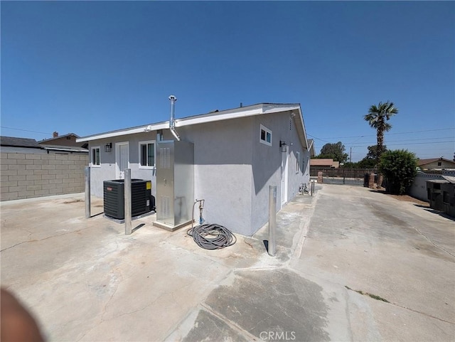 rear view of house with central AC unit and a patio