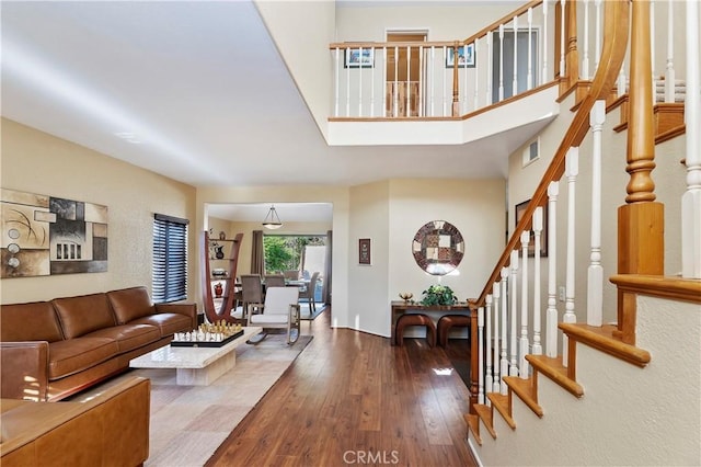 living room featuring wood-type flooring, visible vents, and stairs