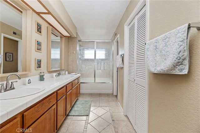 bathroom with combined bath / shower with glass door, vanity, and tile patterned floors