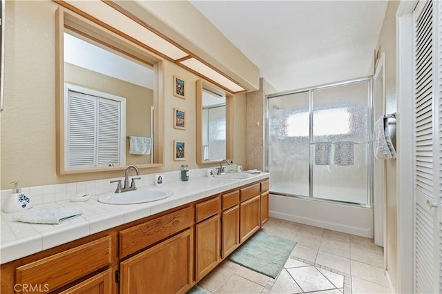 bathroom with double vanity, a sink, combined bath / shower with glass door, and tile patterned floors