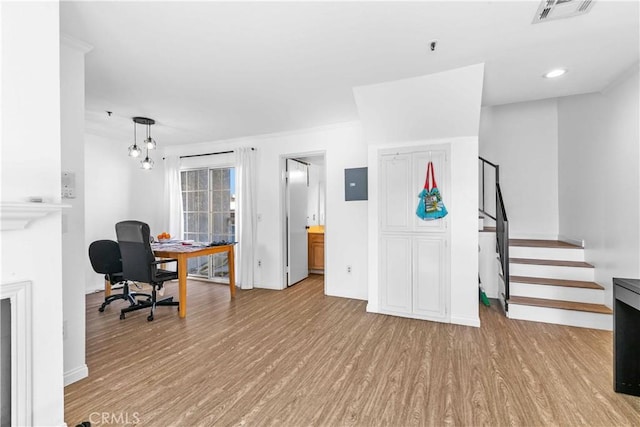 home office with light hardwood / wood-style floors and electric panel