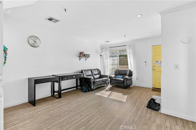 living area featuring light wood-type flooring and ornamental molding