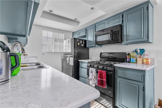 kitchen with a tray ceiling, sink, and black appliances