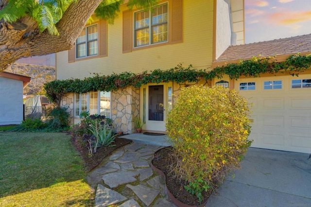 exterior entry at dusk featuring a yard and a garage