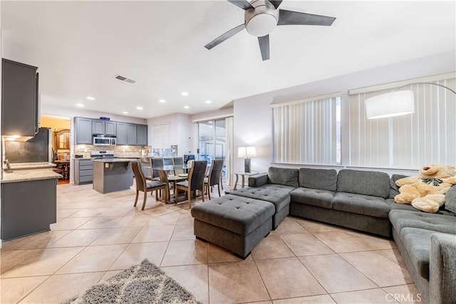 living room with light tile patterned floors, plenty of natural light, and ceiling fan