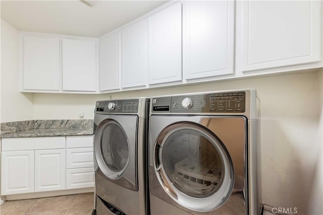 washroom featuring washing machine and dryer, light tile patterned floors, and cabinets