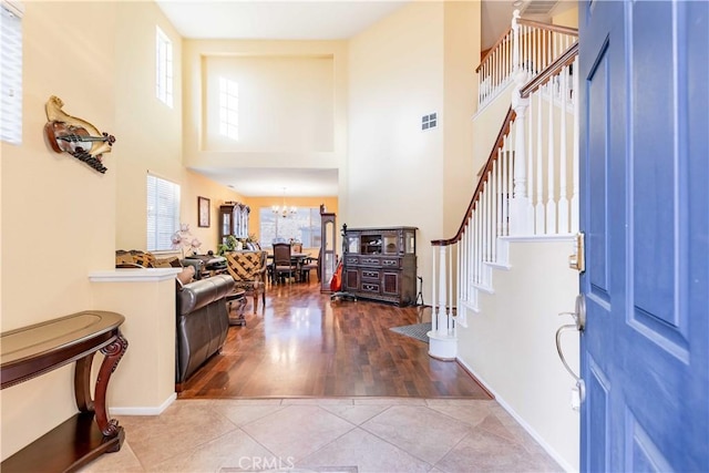 foyer entrance with light tile patterned floors, a towering ceiling, and a chandelier