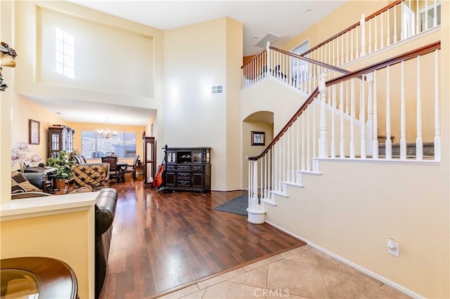 entryway featuring a towering ceiling, an inviting chandelier, and tile patterned floors