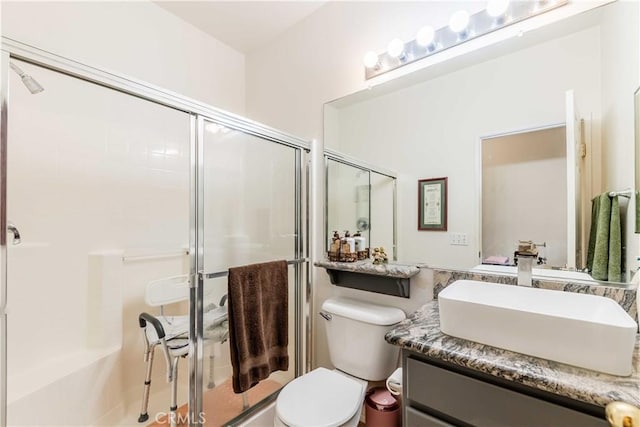 bathroom featuring vanity, a shower with shower door, and toilet