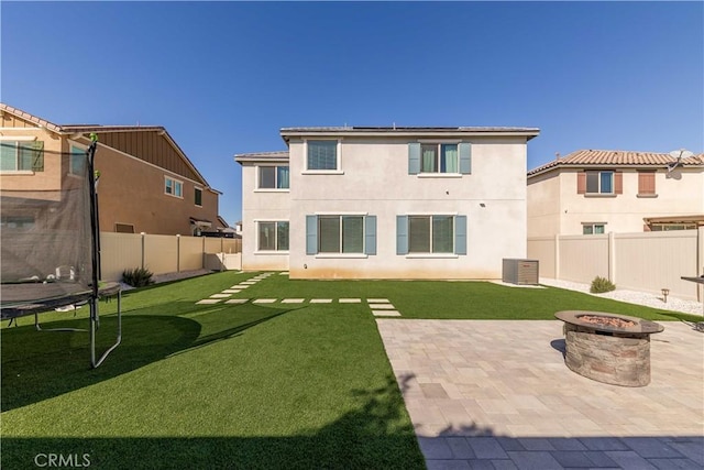 back of house with a yard, a patio, a fire pit, and a trampoline