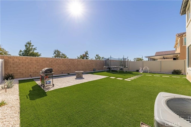 view of yard with central AC unit, a patio area, and a trampoline