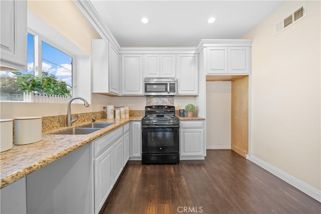 kitchen featuring white cabinets, sink, dark hardwood / wood-style floors, light stone countertops, and black gas range oven