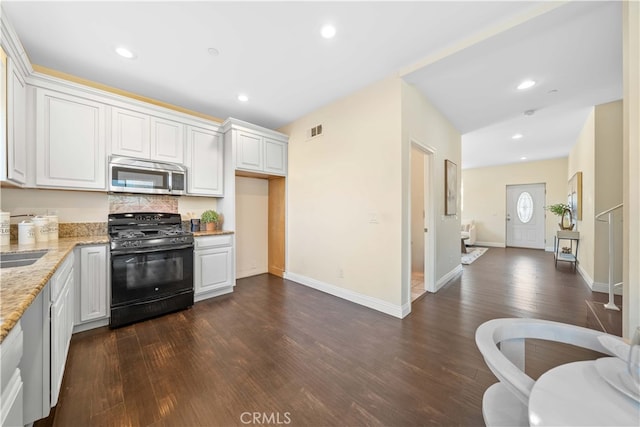 kitchen with black gas range oven, light stone counters, dark hardwood / wood-style flooring, backsplash, and white cabinets