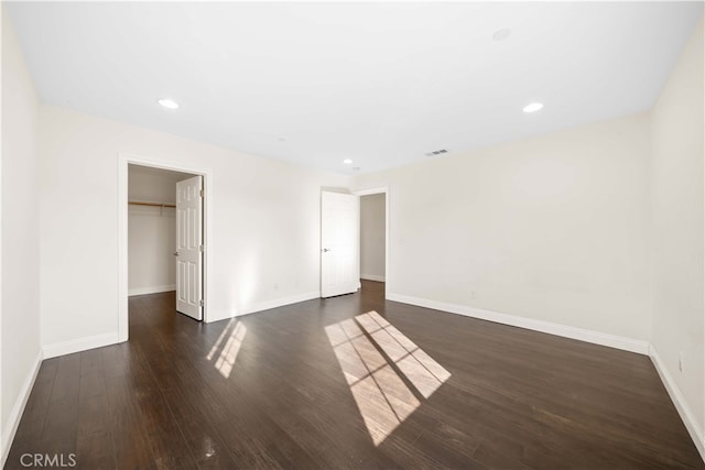 unfurnished bedroom featuring a walk in closet, dark hardwood / wood-style floors, and a closet