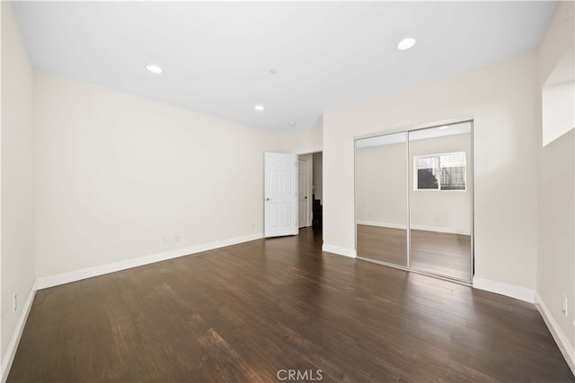 unfurnished bedroom with dark hardwood / wood-style floors and a closet