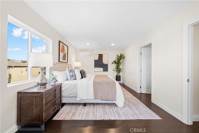 bedroom with dark hardwood / wood-style floors and a wall unit AC