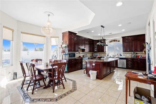 kitchen featuring a center island with sink, light tile patterned floors, pendant lighting, and appliances with stainless steel finishes