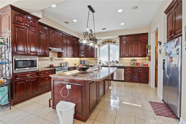 kitchen featuring a center island, hanging light fixtures, light stone counters, light tile patterned flooring, and appliances with stainless steel finishes