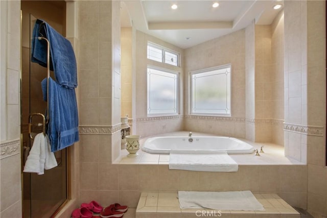 bathroom with a relaxing tiled tub and tile walls