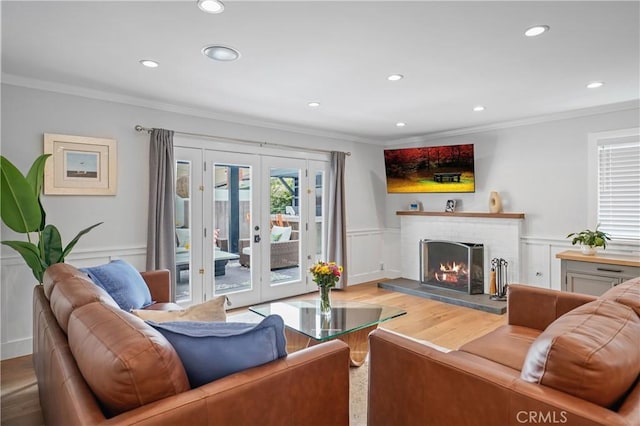 living room with crown molding, french doors, hardwood / wood-style flooring, and a brick fireplace