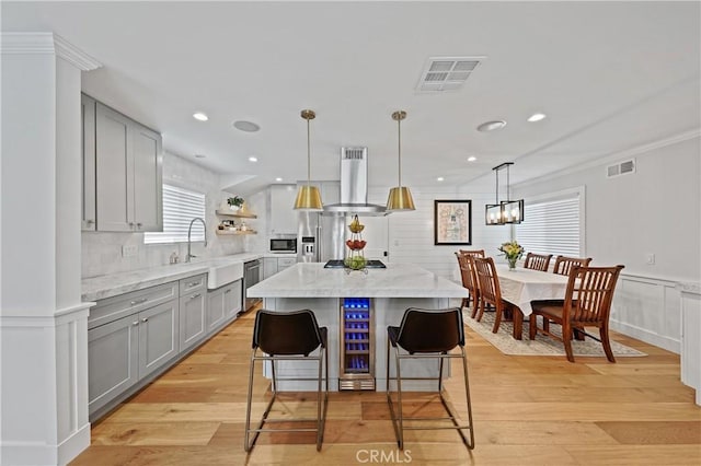 kitchen with appliances with stainless steel finishes, island range hood, sink, a kitchen island, and a breakfast bar area