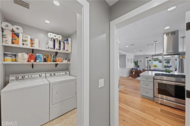 laundry room featuring washer and clothes dryer and light hardwood / wood-style floors