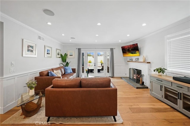 living room featuring light wood-type flooring, crown molding, and french doors