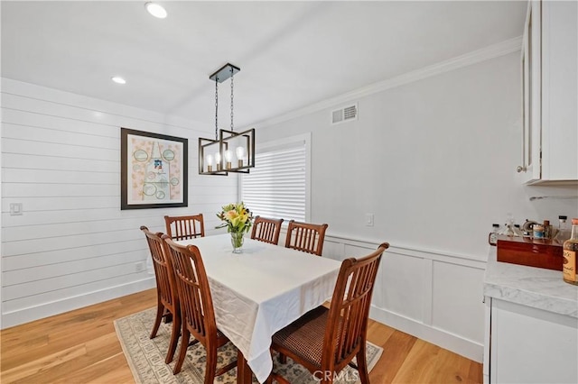 dining room featuring light hardwood / wood-style floors, crown molding, and an inviting chandelier