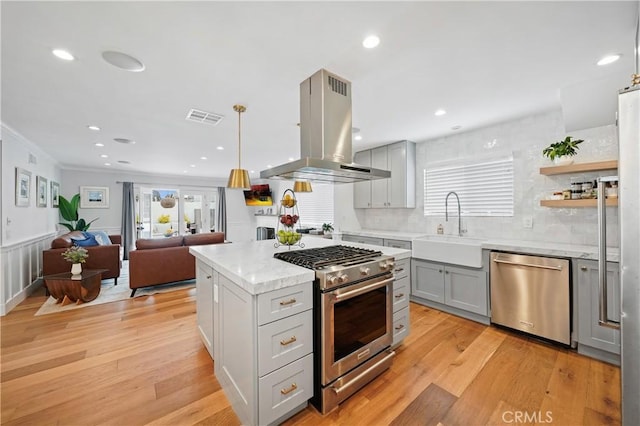 kitchen with pendant lighting, gray cabinetry, sink, island exhaust hood, and stainless steel appliances