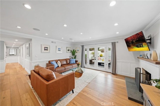 living room featuring light hardwood / wood-style flooring, a brick fireplace, and crown molding