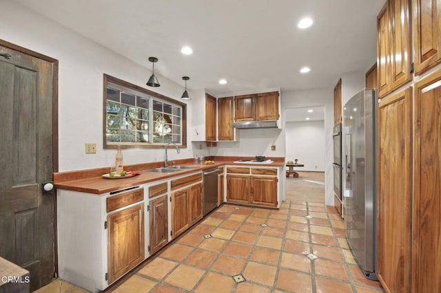 kitchen featuring hanging light fixtures, light tile patterned floors, sink, kitchen peninsula, and stainless steel appliances