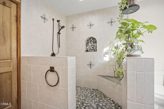 bathroom with toilet and a tile shower