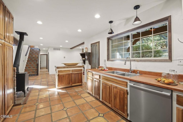 kitchen featuring dishwasher, sink, a wood stove, pendant lighting, and light tile patterned flooring