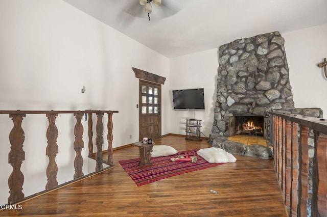 living room featuring hardwood / wood-style flooring, ceiling fan, and a fireplace