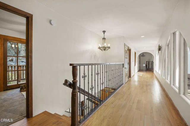 corridor featuring a chandelier, a wealth of natural light, and light hardwood / wood-style flooring