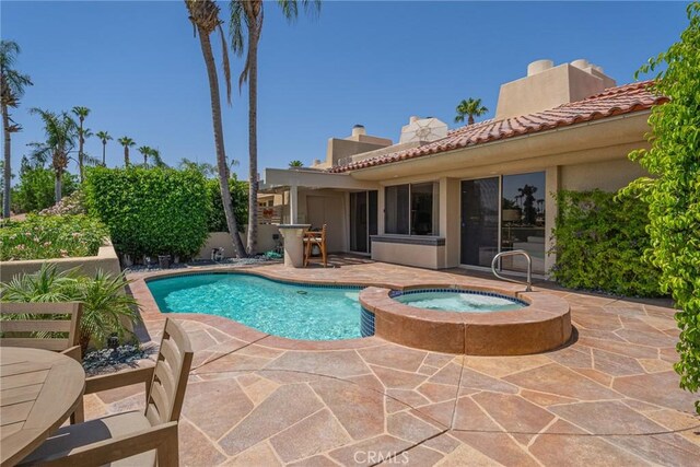 view of pool with a patio area and an in ground hot tub