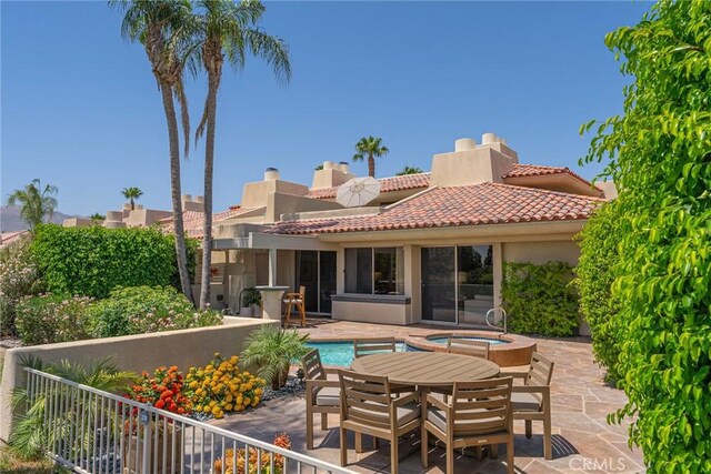 back of house with a swimming pool with hot tub and a patio