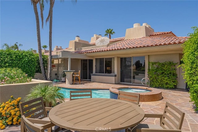 rear view of house with a pool with hot tub and a patio