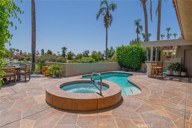 view of swimming pool featuring a patio area and an in ground hot tub