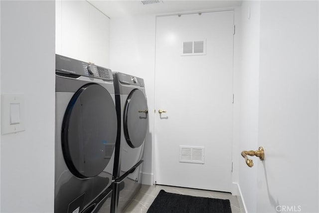 clothes washing area featuring light tile patterned floors and washer and dryer