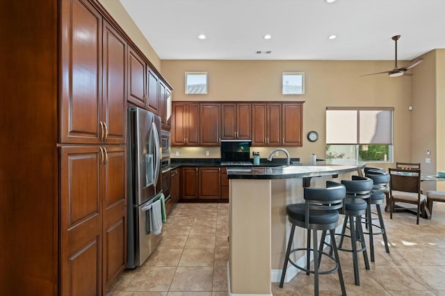 kitchen featuring a breakfast bar, sink, an island with sink, appliances with stainless steel finishes, and light tile patterned flooring