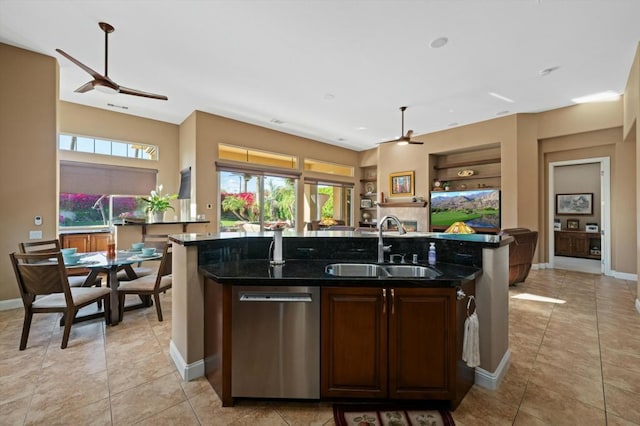 kitchen with dark stone counters, sink, built in features, dishwasher, and an island with sink