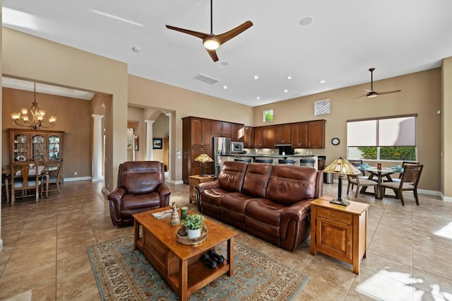 tiled living room with ceiling fan with notable chandelier