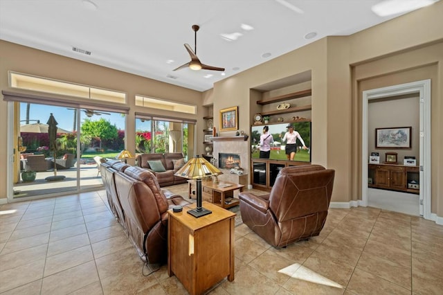 living room featuring built in shelves, ceiling fan, and light tile patterned flooring