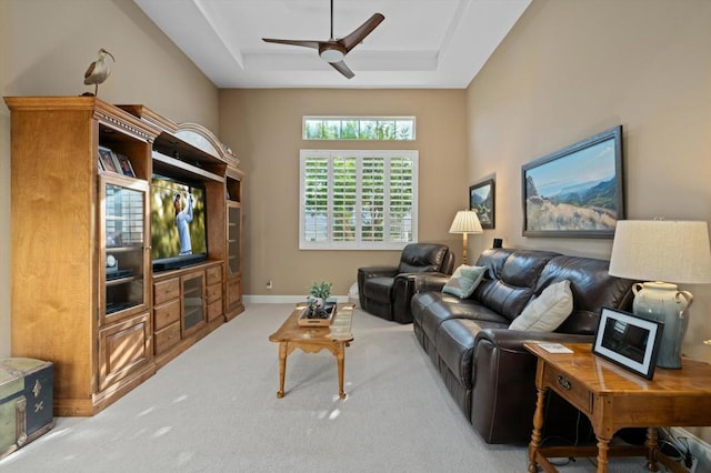 living room with carpet flooring, a raised ceiling, and ceiling fan