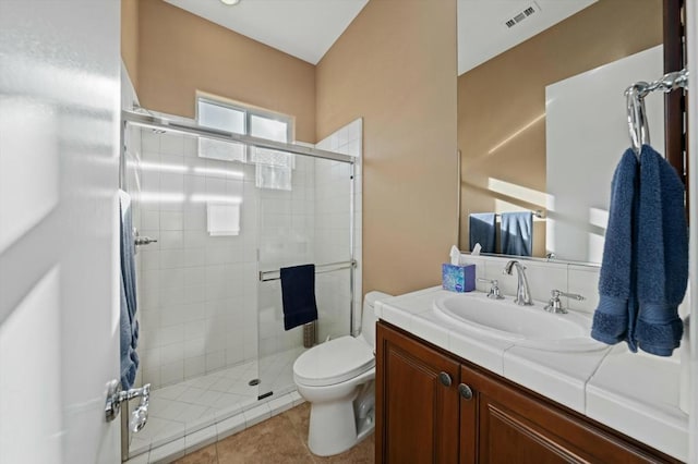 bathroom featuring tile patterned floors, a shower with door, vanity, and toilet