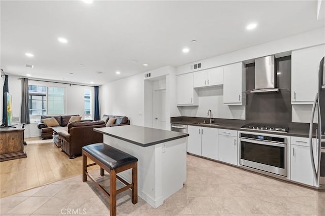 kitchen with white cabinets, stainless steel appliances, wall chimney exhaust hood, and sink