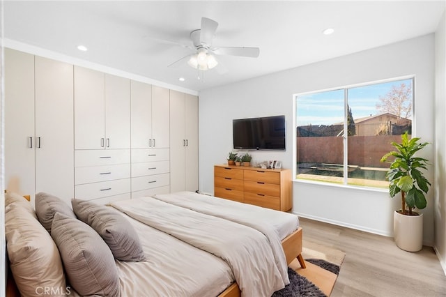 bedroom featuring ceiling fan, light wood-type flooring, and multiple windows