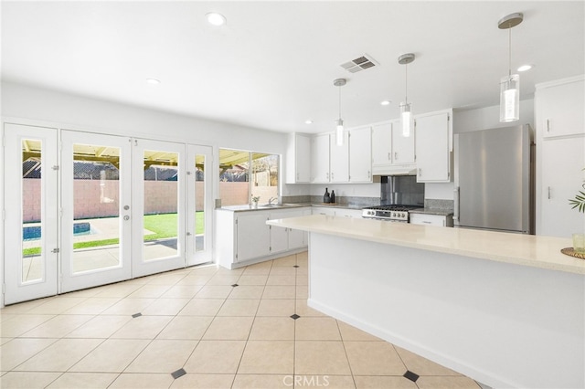 kitchen featuring plenty of natural light, stove, decorative light fixtures, white cabinetry, and stainless steel refrigerator