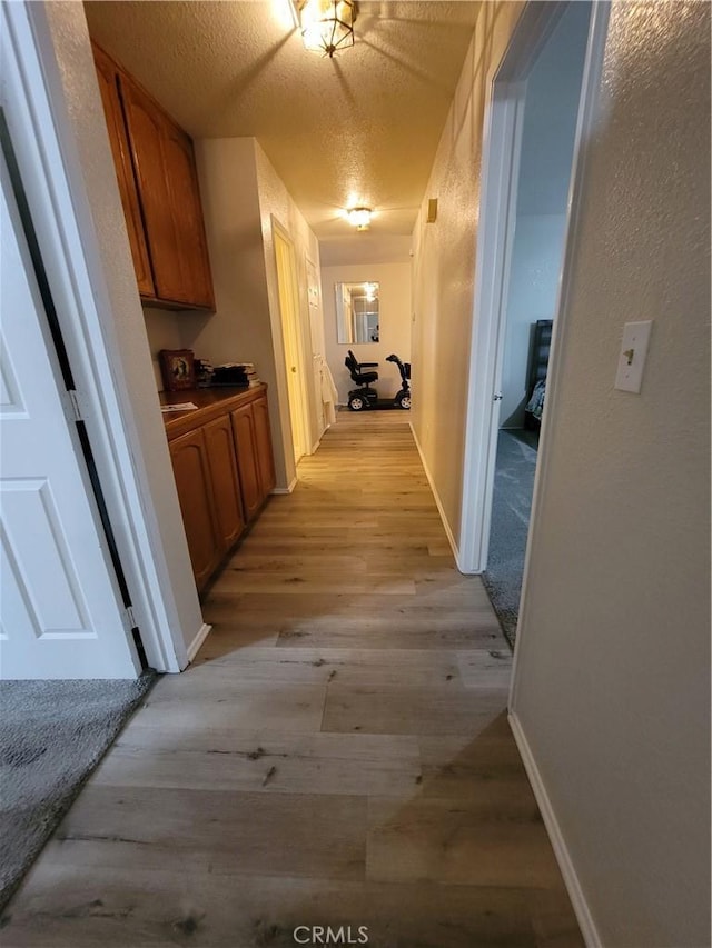 corridor featuring light hardwood / wood-style flooring and a textured ceiling